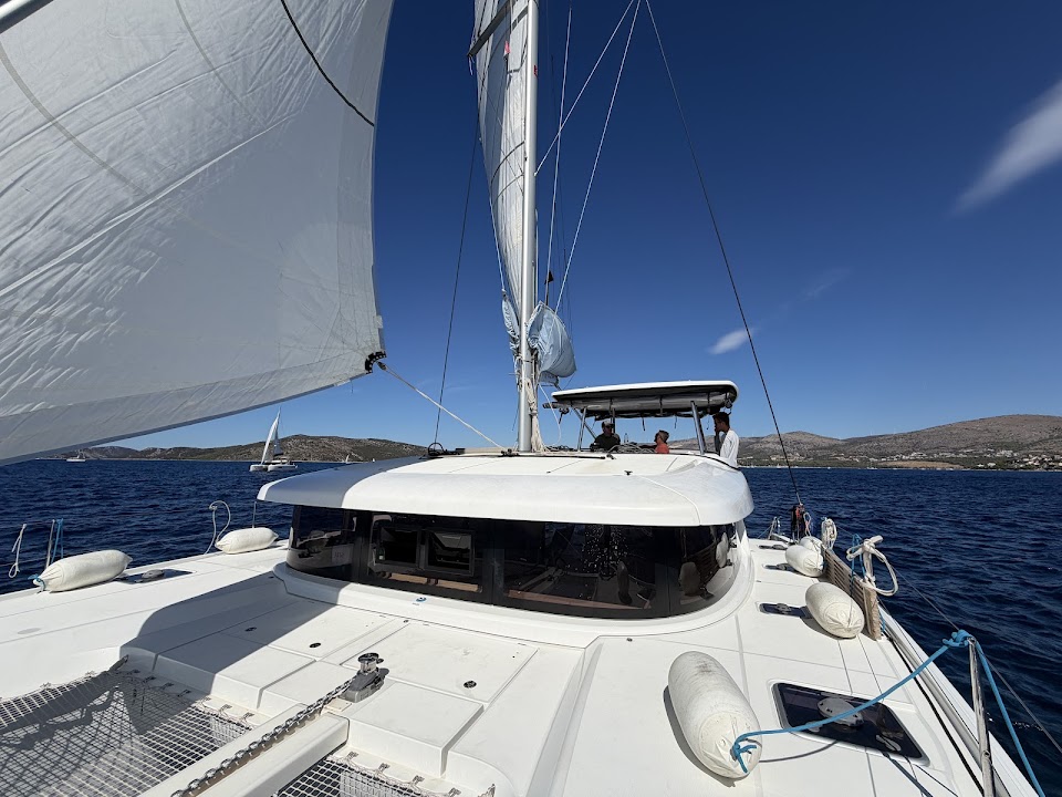 Looking aft from the bow of Seaside Dreams, with sails raised and the crew at the helm